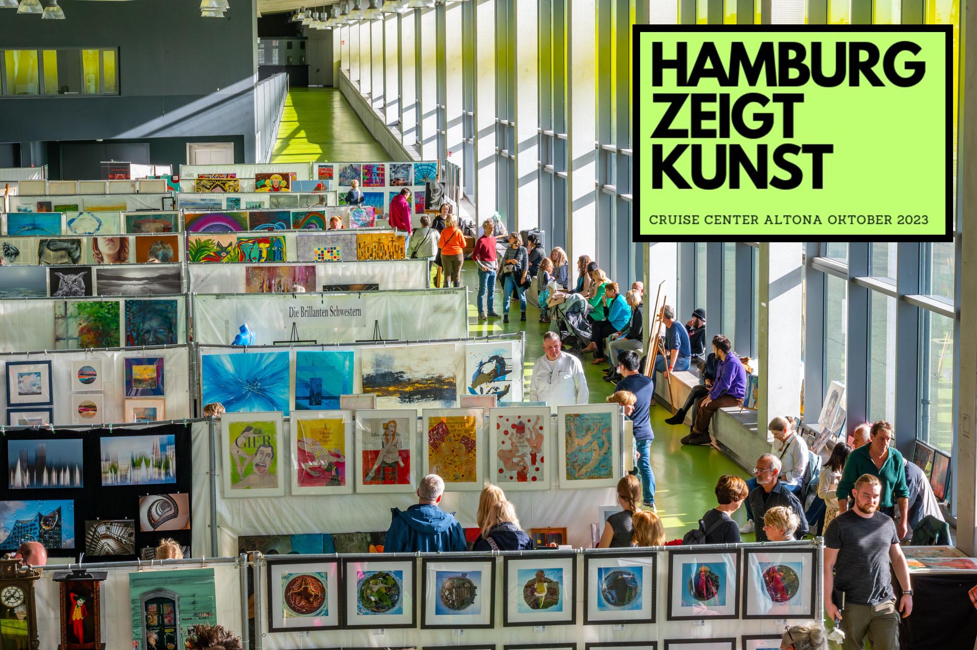 Hamburg zeigt Kunst im Cruise Center Hamburg Altona. Ansicht der Halle von oben auf die Ausstellerwände. Die Wände sind bespannte Bauzäune an denen die Bilder und Kunstwerke hängen. Blick von der Treppe nach Nordosten in die Halle.